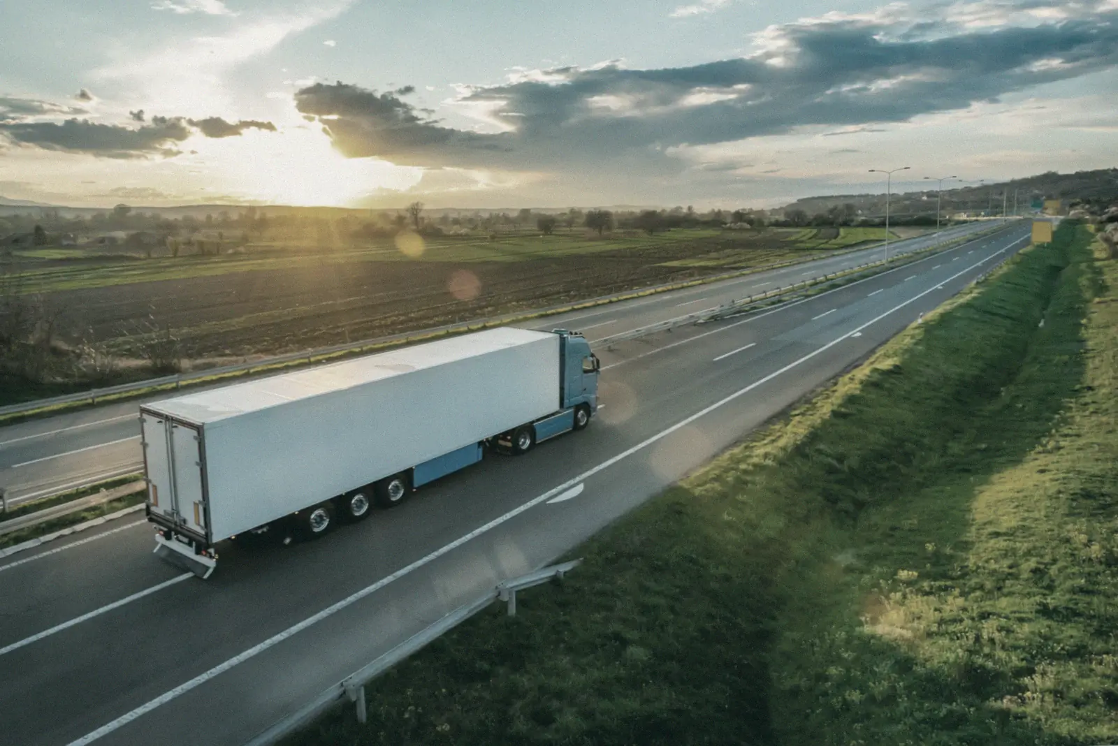 Vrachtwagen met oplegger op de snelweg bij zonsondergang